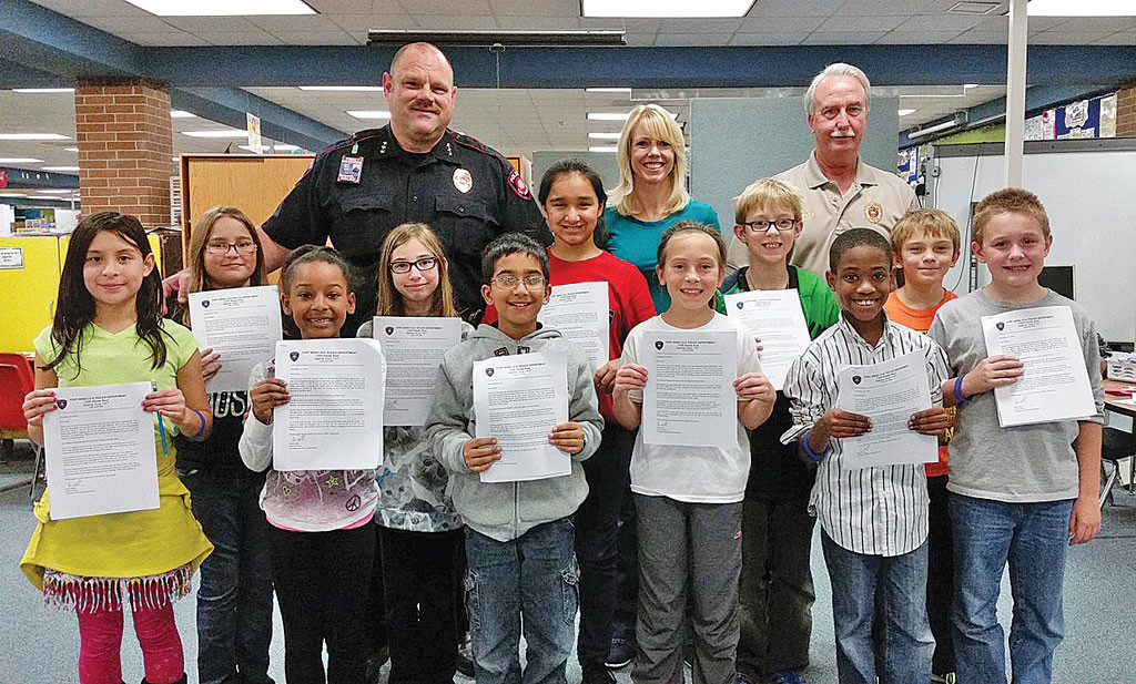 (Front row, l-r): Syan Elmore, Rebeka Garcia, Taryn Gabriel, Alison Kight, Abiral Gnyawali, Jalena Johnson, Lucy Hailey, Tynan Weber, Mikhail Keasley, and Cade Hoffman; (back row) David Rider, Chief of Police; Stacy Garcia, fourth-grade teacher; and Mike Harvey, Police Sergeant.