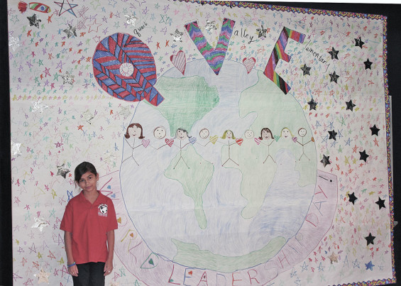 QVE student Anjolina Jimenez stands next to a poster she designed for "World Leadership Day."