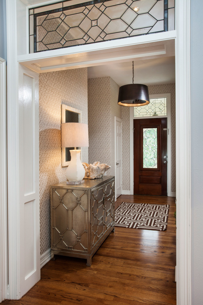 The entryway received a total makeover in stunning wallpaper from Schumacher. A German silver hammered cabinet from Arteriors fits the space well. 