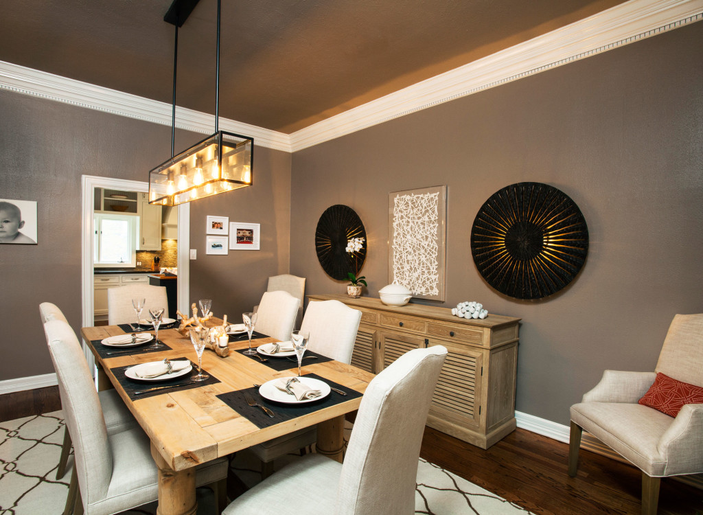 Warm walls with a darker ceiling color add drama in the dining room. The table and chairs are from Restoration Hardware; the chandelier is from Arteriors. An unexpected surprise comes in the form of the two art pieces on the wall that are actually sconces. (also Arteriors)   |  Simple, elegant table settings adorn the dining room table.