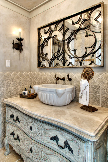 In the powder room, the chest, perfect in scale, was altered in finish by Segreto to complement the plaster waxed walls and lovely tile wainscoting. Sources: French iron grate mirror from The Original Round Top Antiques Fair. Sink from Chateau Domingue. Plaster walls and chest finish by Segreto.