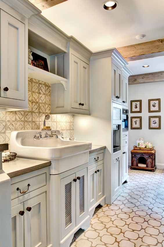In the mudroom, backsplash and handmade terra cotta tiles from Architectural Design Resource, exposed beams (faux-finished to look old) and a farmhouse kitchen sink make this space chic and inviting.