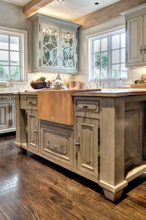 The custom island in the kitchen features a butcher block, a sentimental piece that has been in every home Gene has owned, inset into French Oak. The cabinets, finished by Segreto Finishes, are all raised to resemble pieces of furniture. The hardwood floors throughout the home are waxed red oak with ebony stain, added after the homeowners moved in.