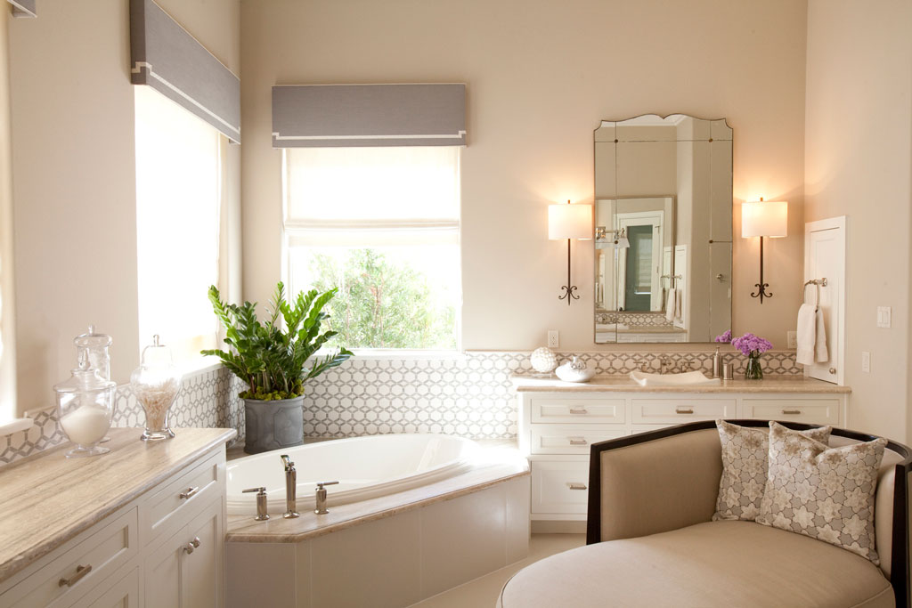 The master bath follows the neutral color palette and extends the use of Calacatta Marble to the countertops. Travertine tile floors and tub backsplash from Walker Zanger finishes the look. A chaise lounge provides just the right touch of leisure glam.