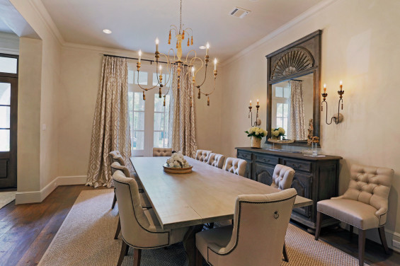 In dining room, a French sideboard was found in Round Top. Mirror and chandelier from Memorial Antiques & Interiors. Rug by Creative Flooring and window treatment by Linda Falk. Custom-built table seats 12 for their ever-growing family.