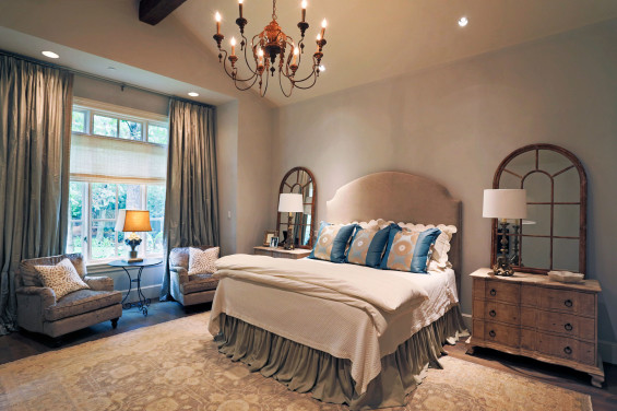 The master bedroom is draped with custom linens as well as a coverlet and duvet by Kuhl Linscomb. The headboard is a custom design and made by Hien Lam, as well as the chairs. The arched mirrors are a lovely backdrop to the Aiden Gray lamps and dressers found in Round Top. Window shades by the Shade Shop.