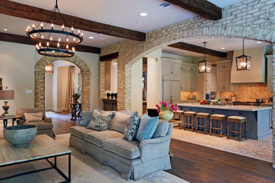 Antique beams are the tie that binds the kitchen and the family room. Shades of blue in the island also tie into the pillows on the sofa to allow the rooms to blend seamlessly.