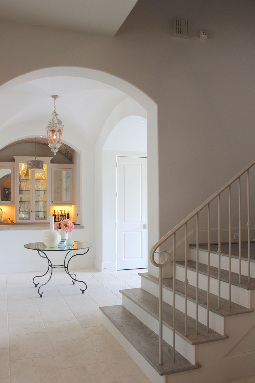 The entry sets the stage for simple elegance. The wooden aged lanterns are from Aiden Gray and the mirror and iron table is a custom piece. An uncluttered foyer allows for an unobstructed view through the home.