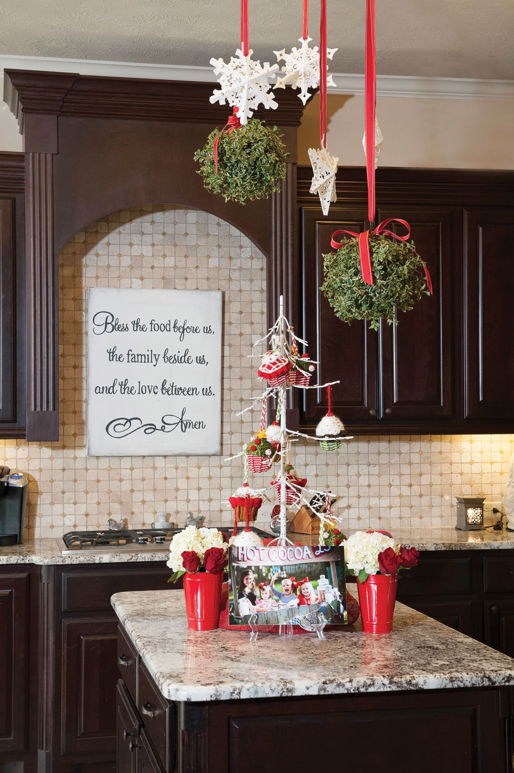 Fresh kissing balls hang from the ceiling over the kitchen island giving guests a chance to kiss under the holly!