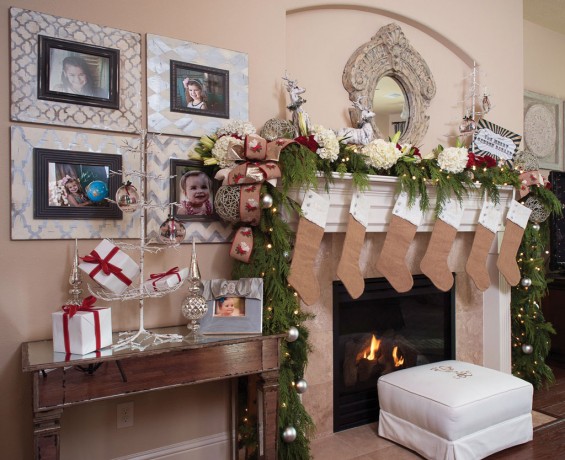 Fireplace mantle is decorated with monogrammed linen stockings, fresh florals and greenery and oversized ornaments and ribbon.