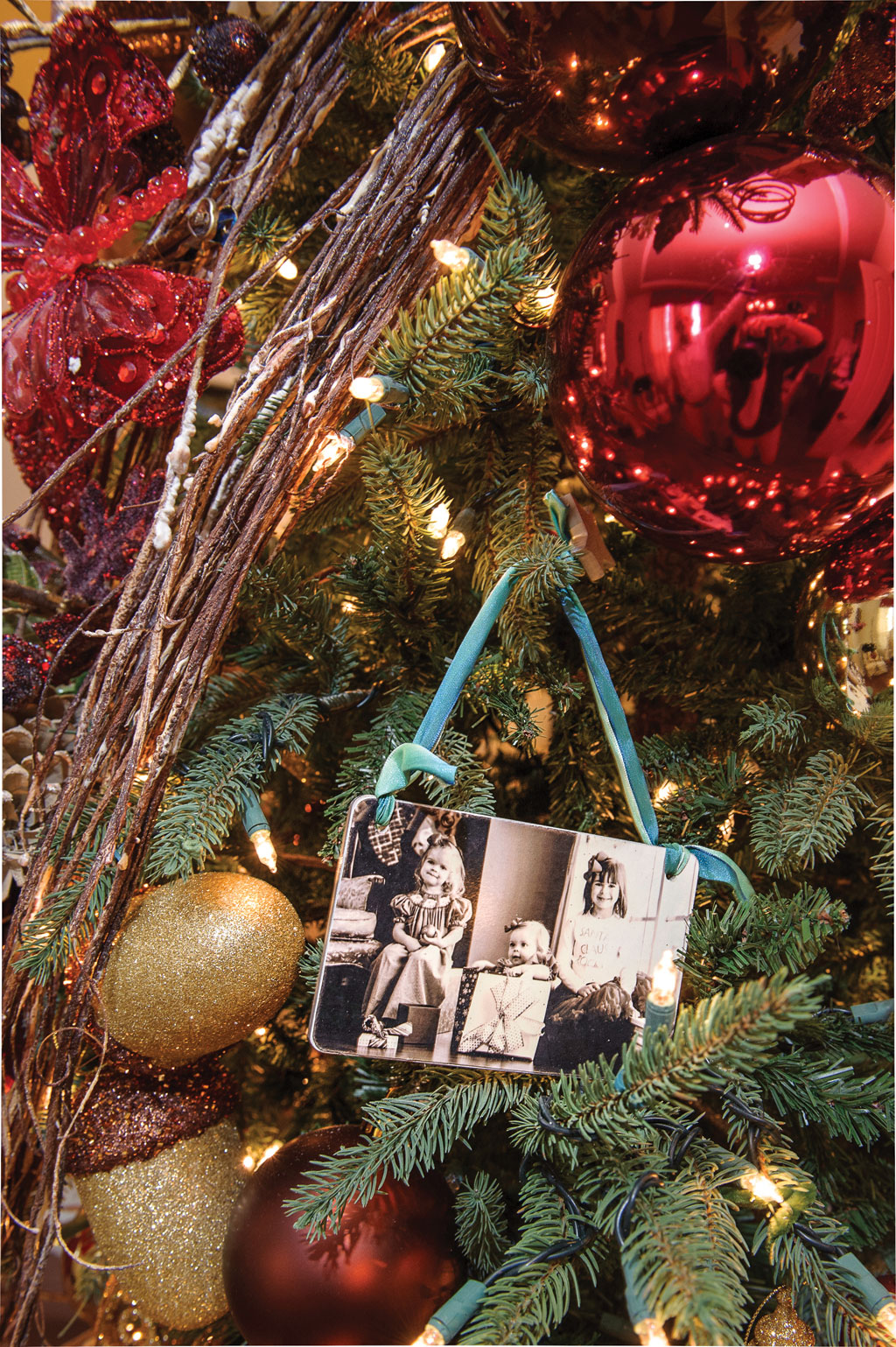 A close-up of the Christmas tree in the entry reveals a custom photo ornament of the three daughters.
