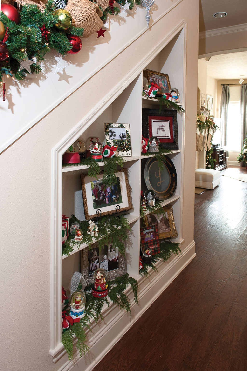 The family's unique snow globes from their travels and holiday events are on display beneath the staircase, along with fresh garland and family photos.
