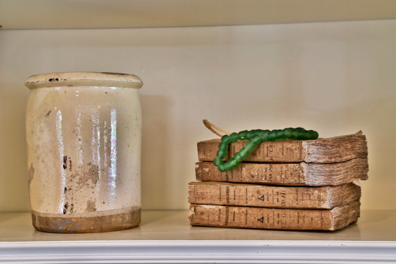 Interesting accessories abound in this home. A French confit jar, old French paper books and African beads make a visionary statement in a living room bookcase.