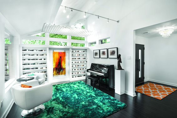 View of the lounge and entry. The wine shelf makes good use of the shallow depth and displays wine from around the world. Light from the telescoping heads on a monorail provide filtered light through the original 1950’s screen painted in iridescent white. The screen, which was formerly a room divider, now is an interesting work of art which the homeowners refer to as the “Cloud.”