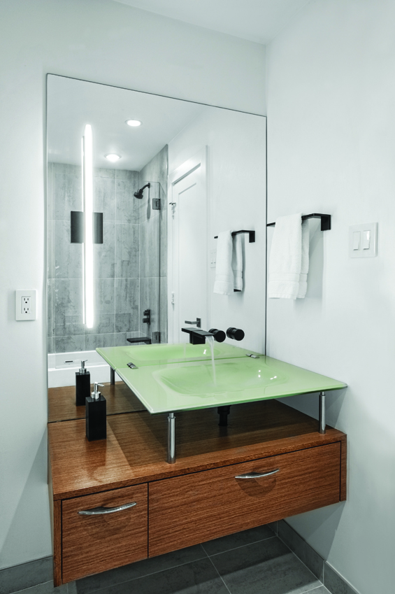 Black Deque fixtures by Dornbracht and an offset Sonneman Stiletto bath bar are an unexpected pop against white walls and pearl gray Aparici tile from La Nova.