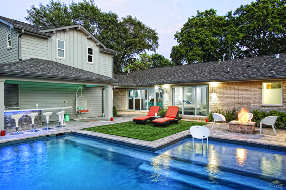 This backyard is the ultimate entertainment venue for any season complete with outdoor kitchen and bar, pool with sun shelf, and a fire pit. Pool by 149 Pool, Ben Krywick. Landscape by Landscapes by Rene.