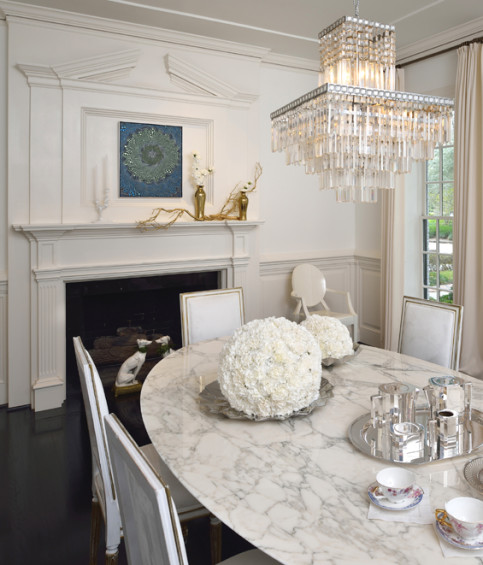 In the dining room, charming carnation balls sit on a Saarinen dining table under a vintage chandelier found at Brown. Art by Barbara Takenaga.