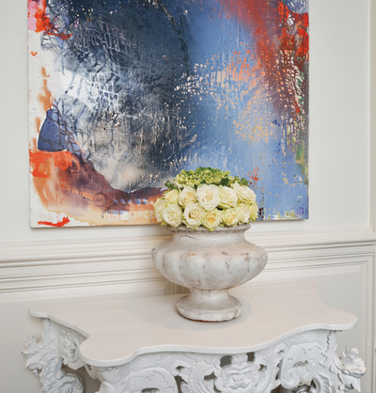 A vintage concrete garden vase is adorned with roses. Art by Jackie Saccoccio.